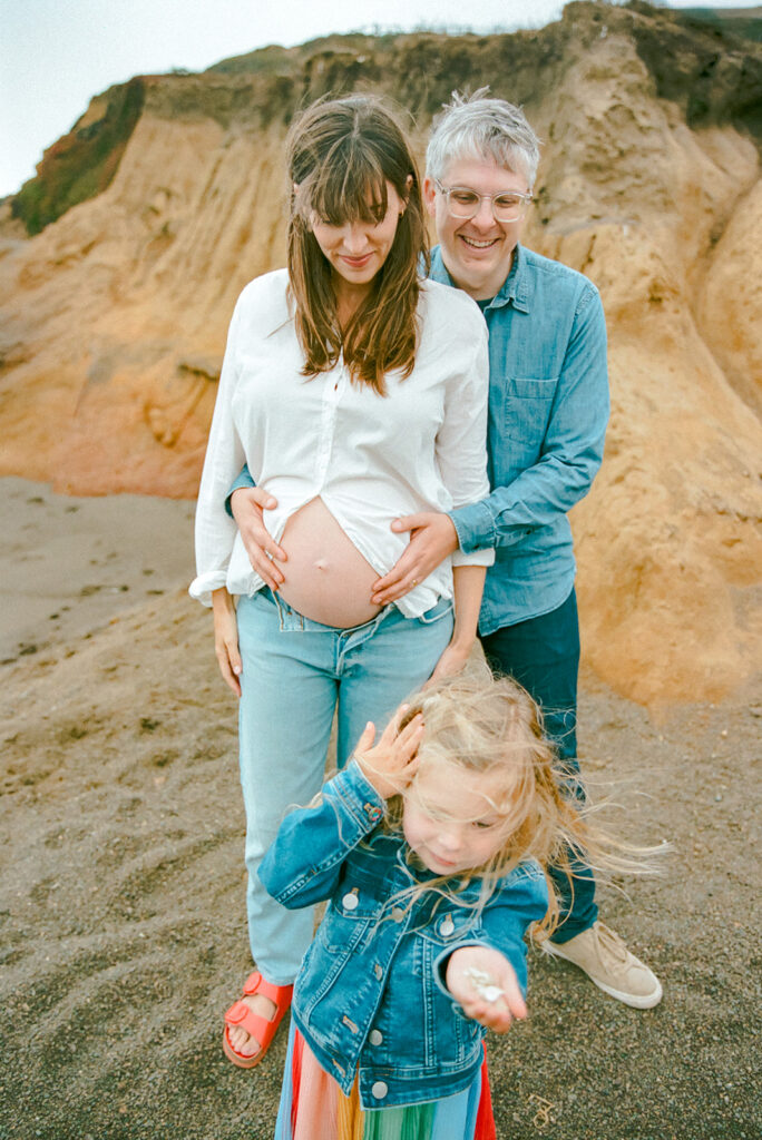 Family maternity portrait at Rodeo Beach with coastal cliffs in Marin County on 35mm film.