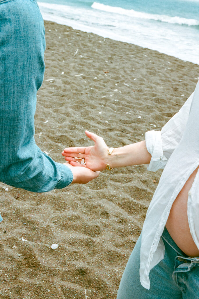 Woman handing her husband seashells on the beach.