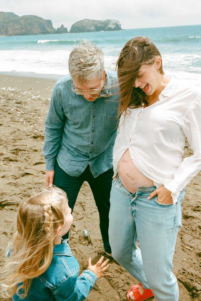 Family of three having fun on the beach during Bay Area maternity photography at Rodeo Beach in Marin Headlands. 