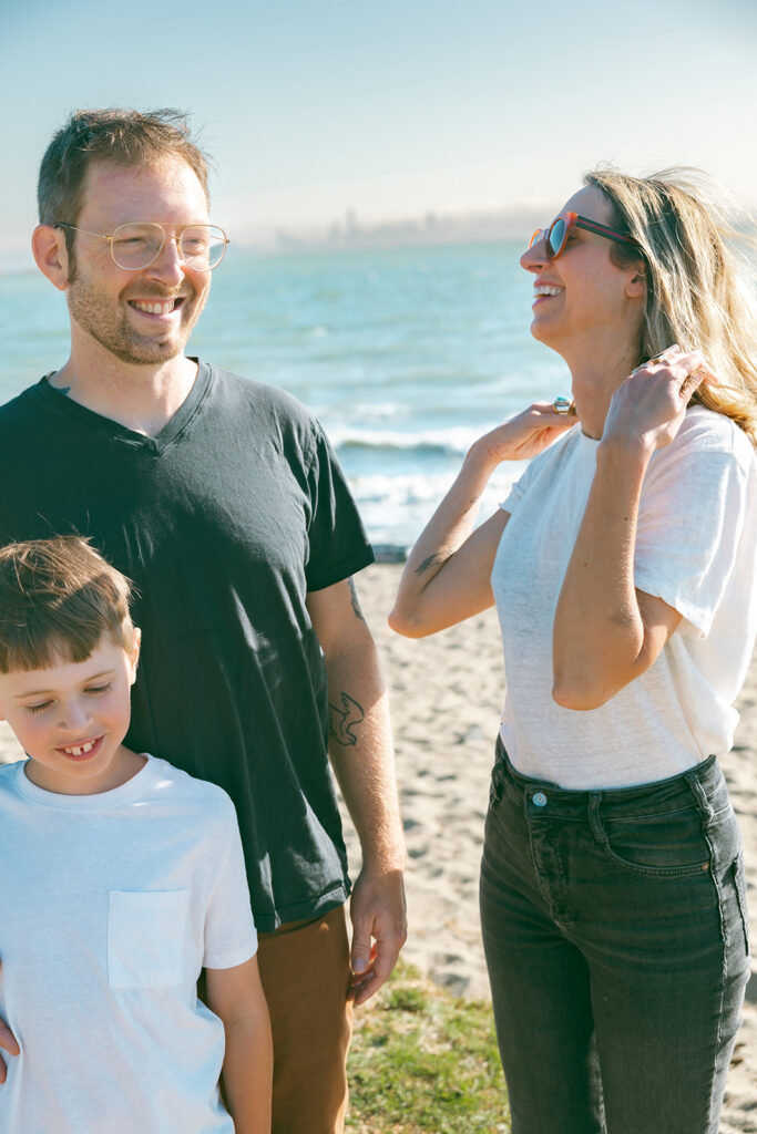 Family of three laughing together in a candid photo at Albany Bulb in the East Bay of California. 