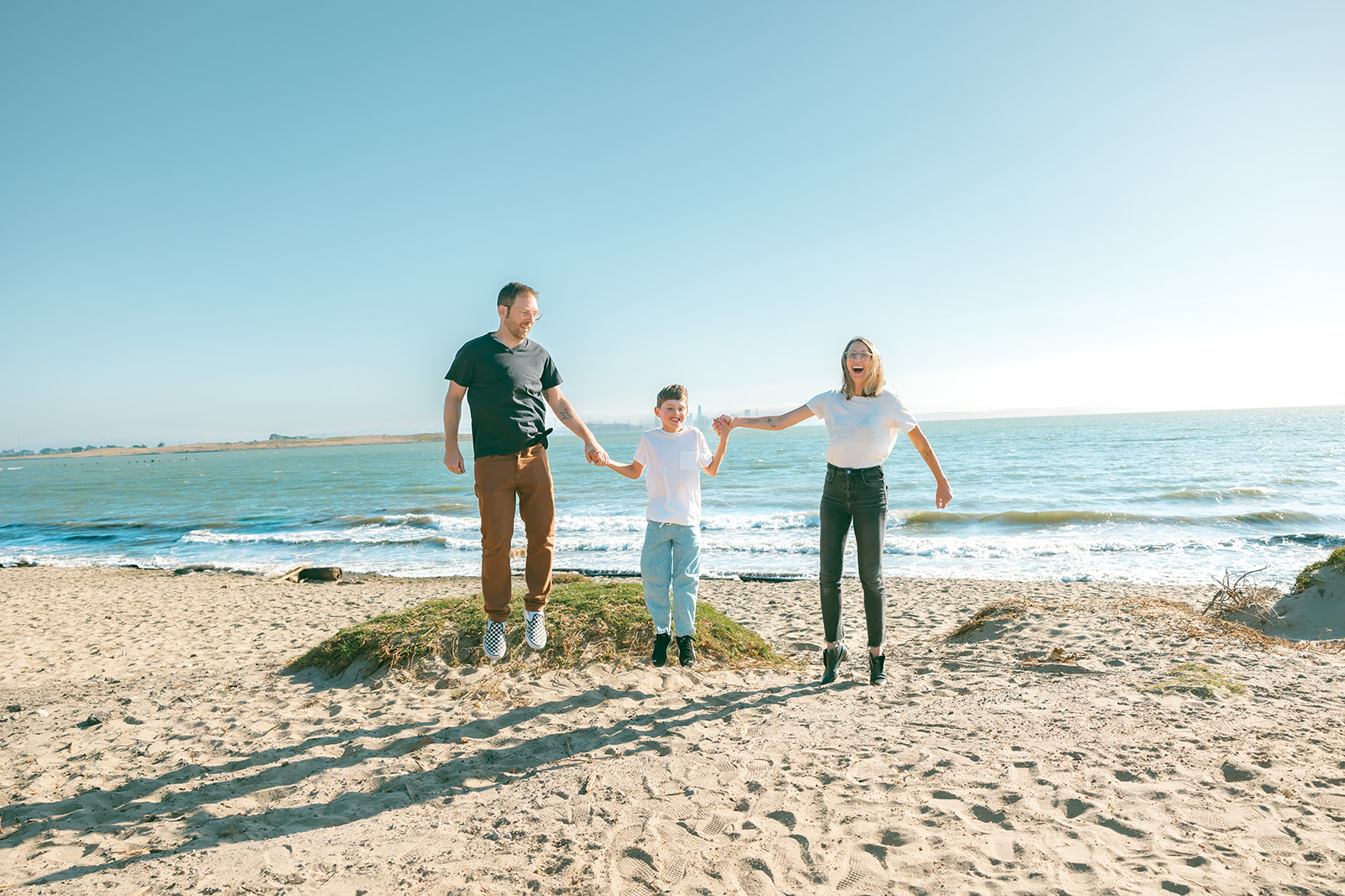Family jumping together on the beach during an East Bay family photo session at Albany Bulb.