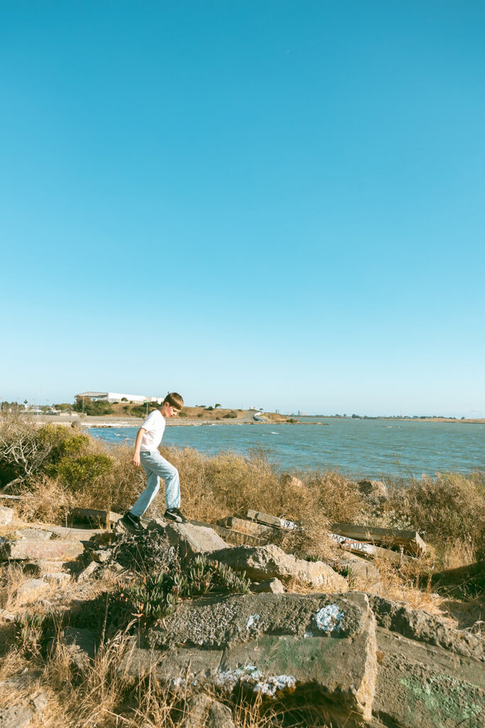 Young boy walking along rocks and stones at Albany Bulb in the East Bay of California. 
