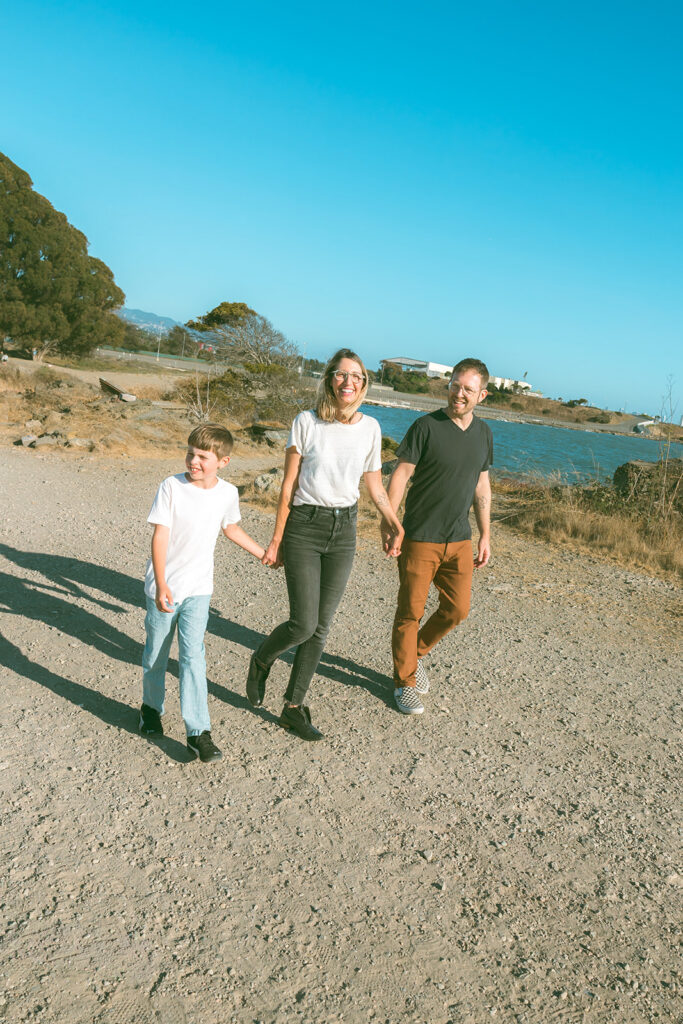 Family of three holding hands and walking together at Albany Bulb in the East Bay. 
