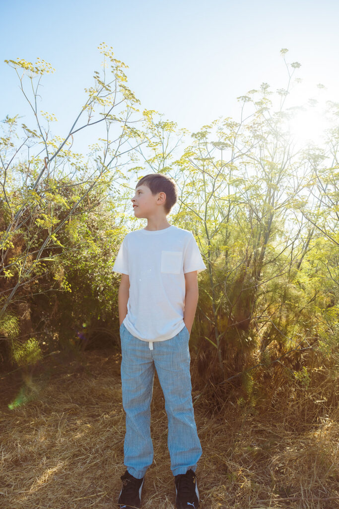 Young boy posing in front of wild flowers at Albany Bulb in the East Bay of California. 