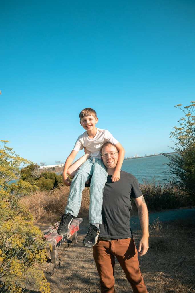 Man holding his son on his shoulder at Albany Bulb in the East Bay. 