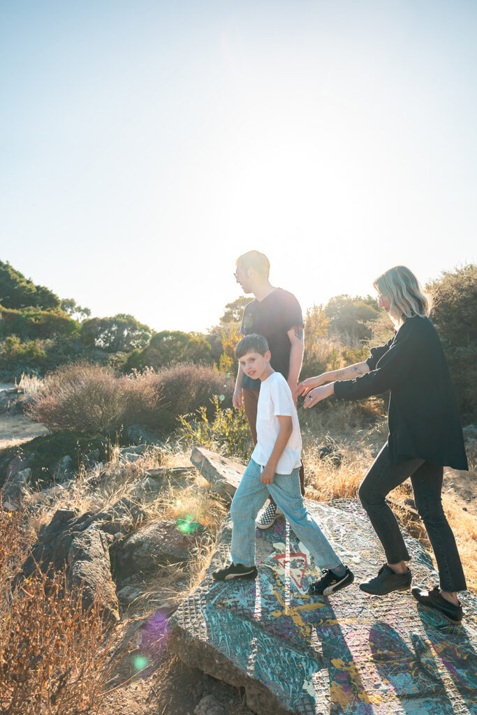Family of three walking along the colorful rocks at Albany Bulb. 