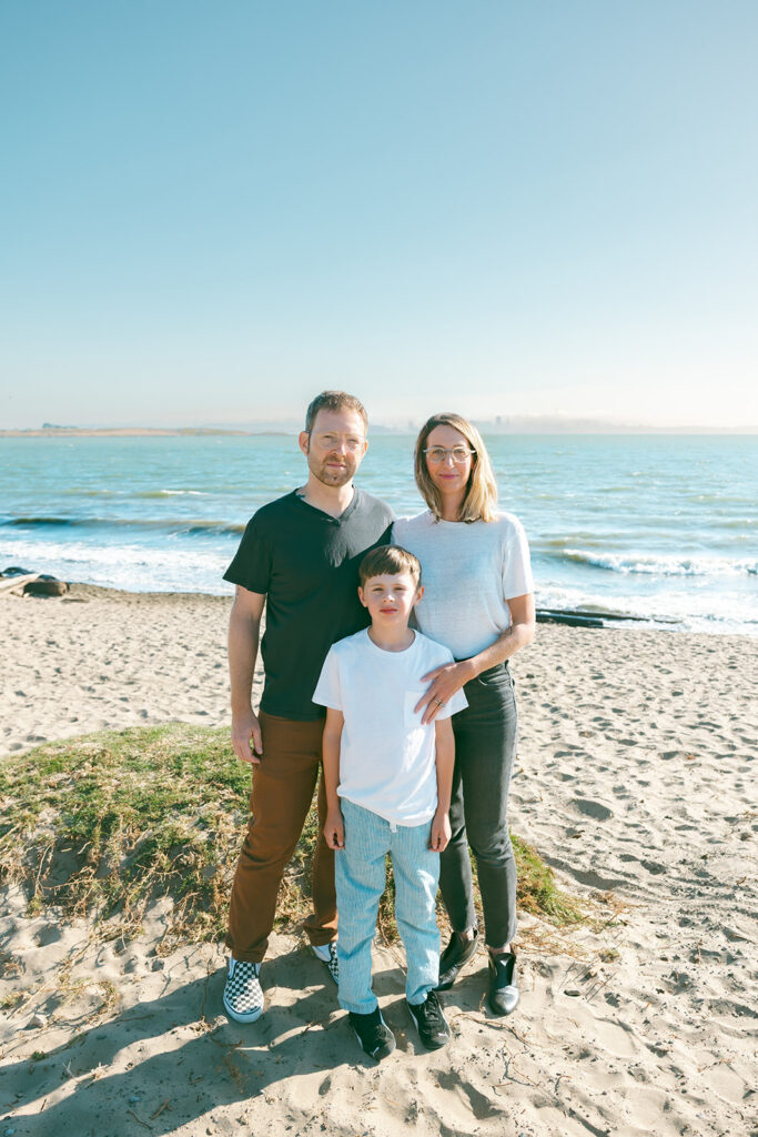 Family of three posing on the beach at the Albany Bulb in the East Bay.