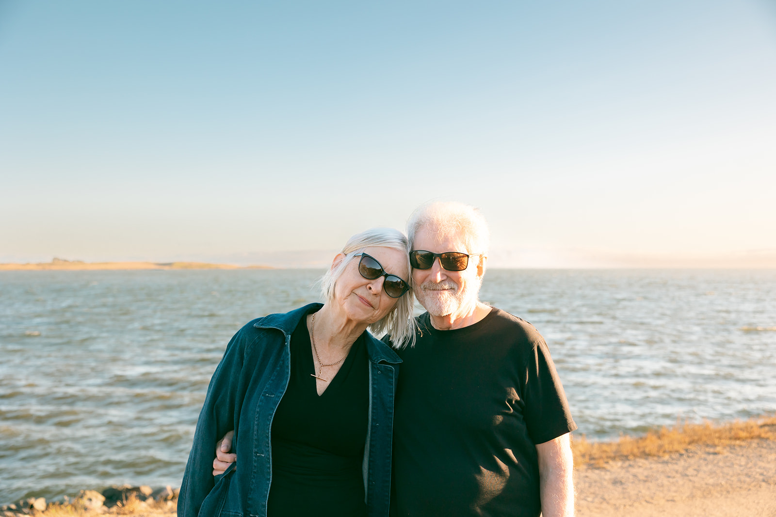 Couple posing together in front of the San Francisco Bay at sunset.