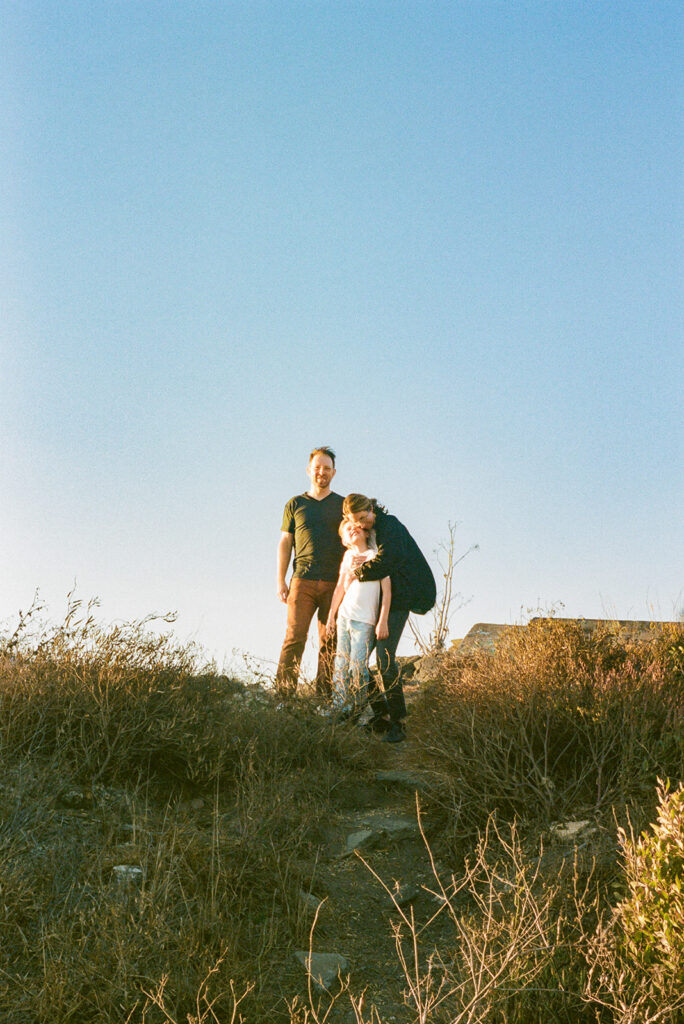 Family of three posing at the top of a trail on 35mm film in the East Bay. 