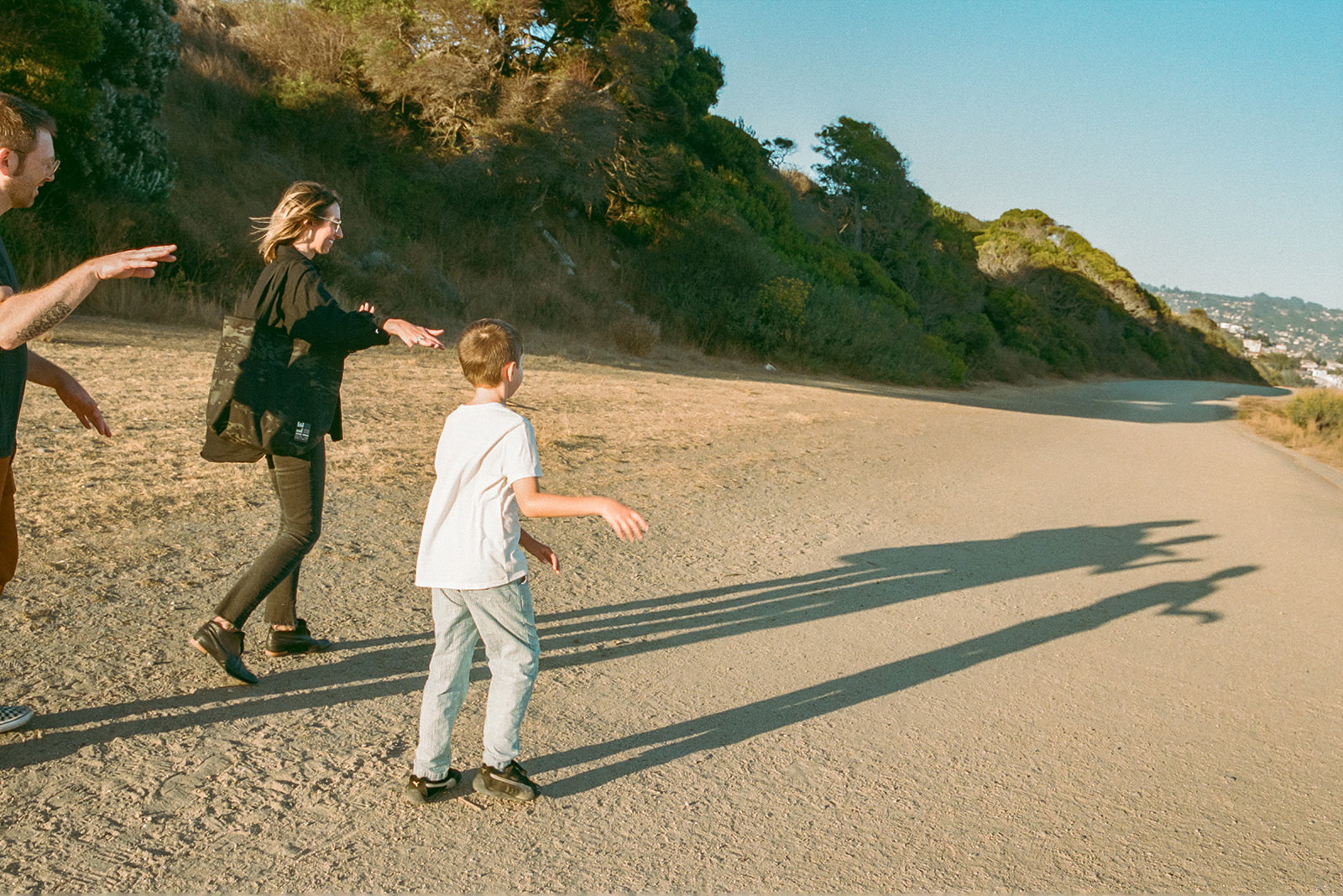 Candid film image of family walking along sunlit trail during East Bay outdoor photo session.
