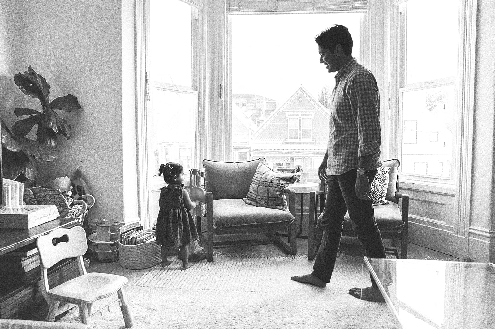 Black and white candid photo of a father and daughter in their living room during their at home family photos in San Francisco. 