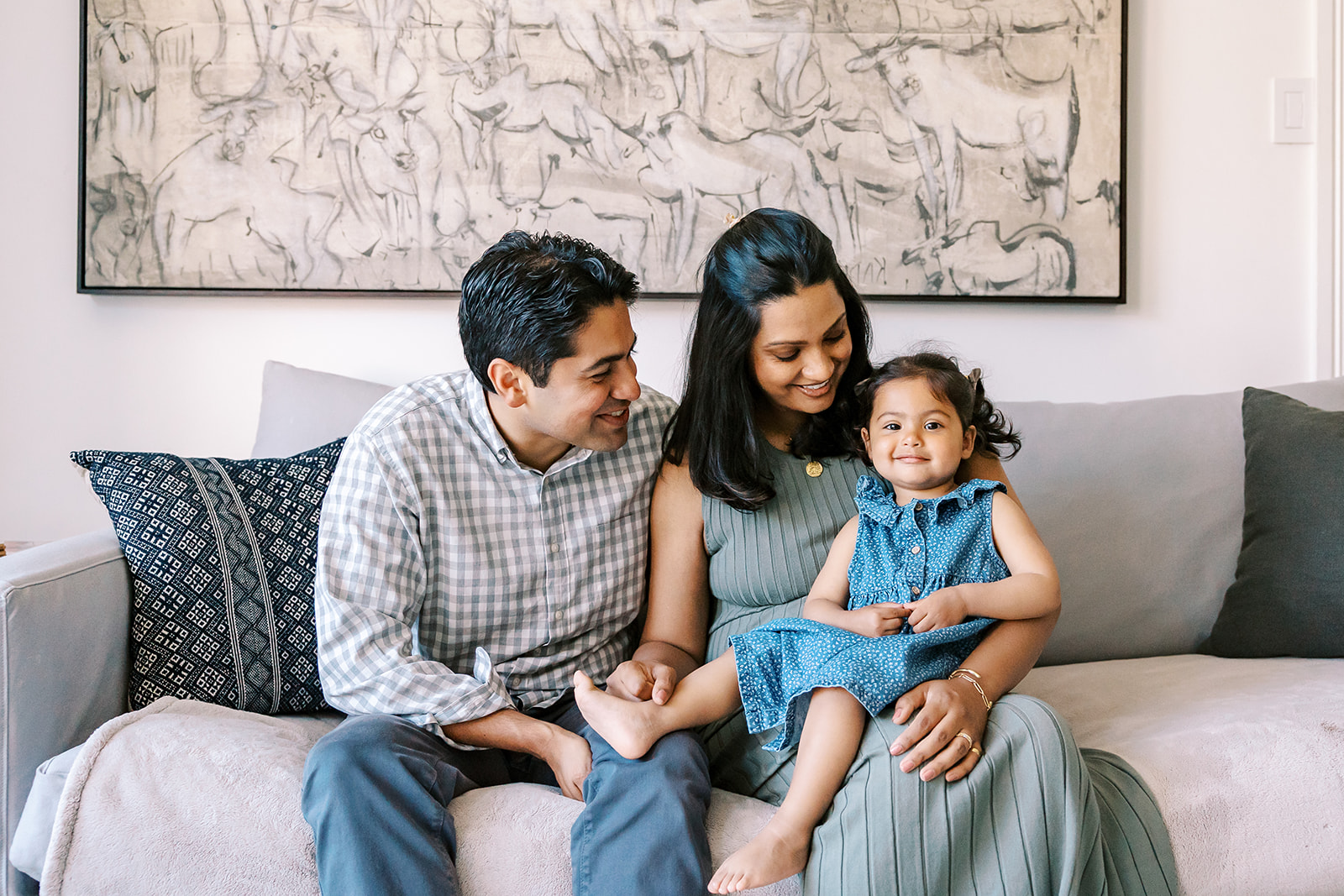 Family of three posing on the couch during their at-home family San Francisco maternity photos.