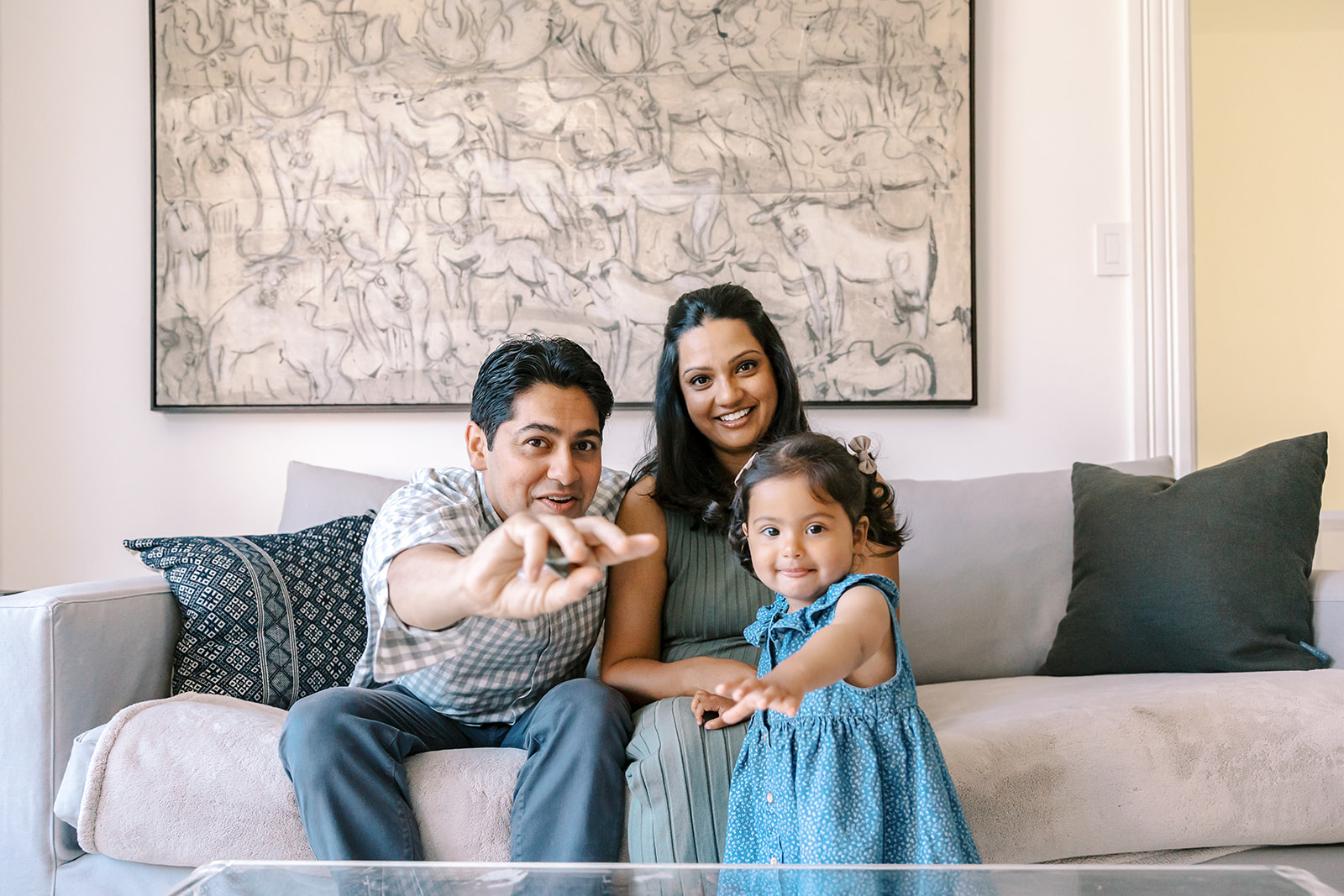 Family of three posing on the couch during their at-home family San Francisco maternity photos.