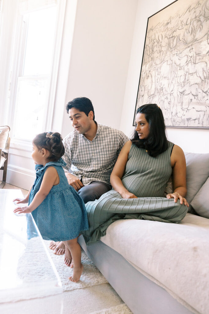 Family of three posing on the couch during their at-home family San Francisco maternity photos.