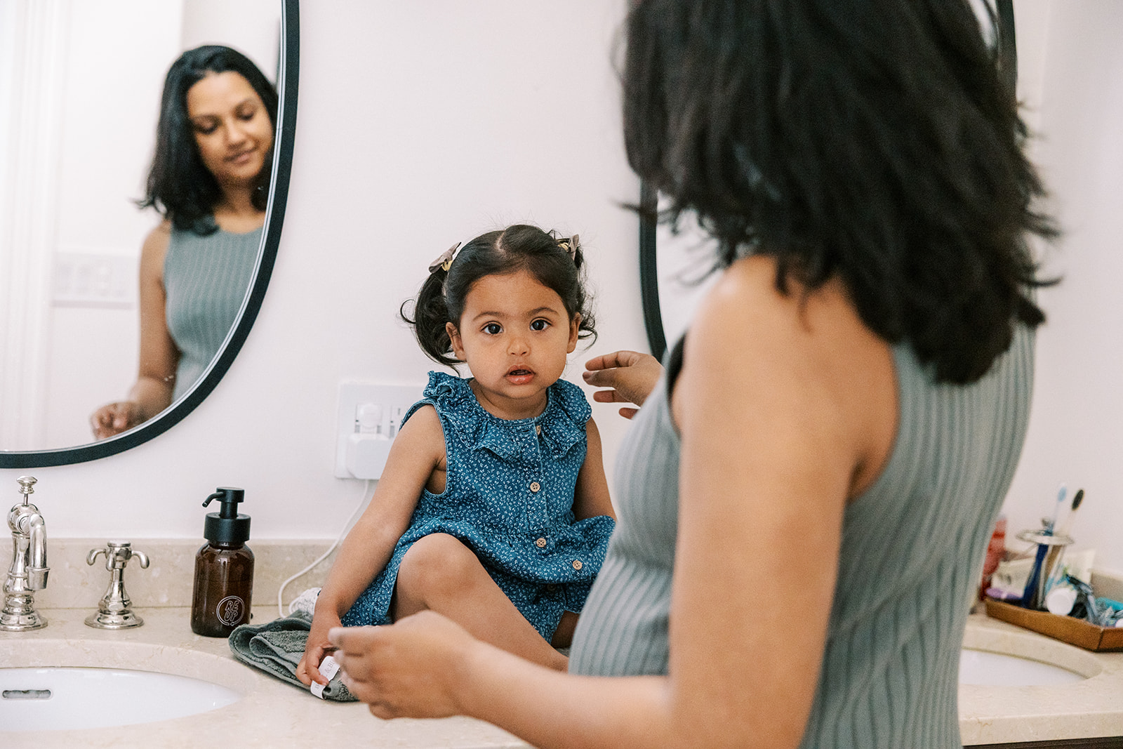 Mother adjusting her daughters hair on the bathroom counter at the start of their at-home family photos in San Francisco.