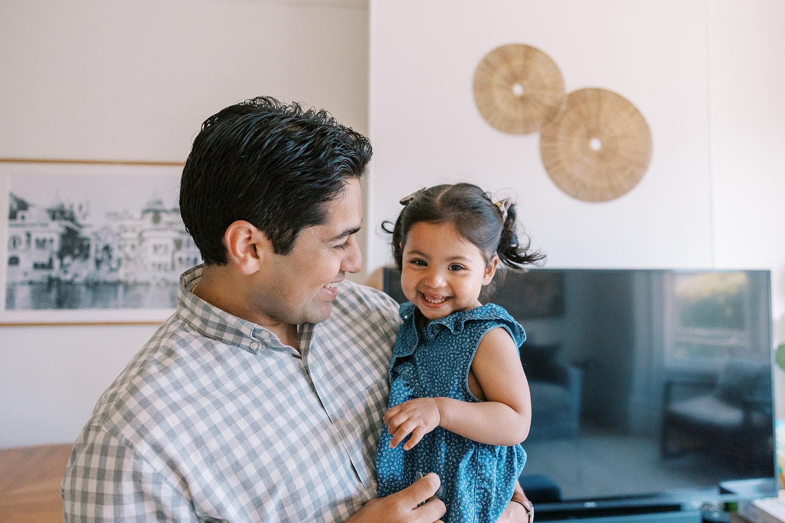 Father holding his daughter and smiling in their home.