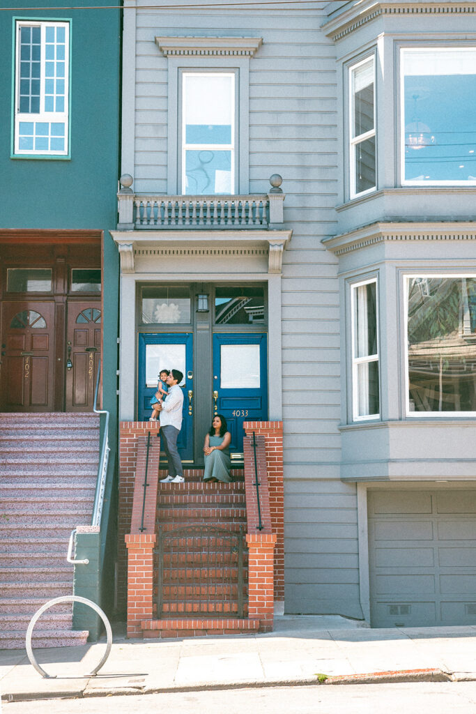 Family of three posing on their outdoor steps during their family and San Francisco maternity photos at home.