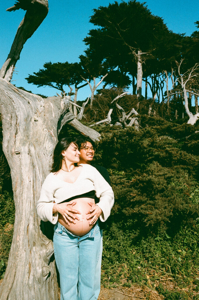Couple smiling and leaning against a tree captured on film at Lands End in SF.