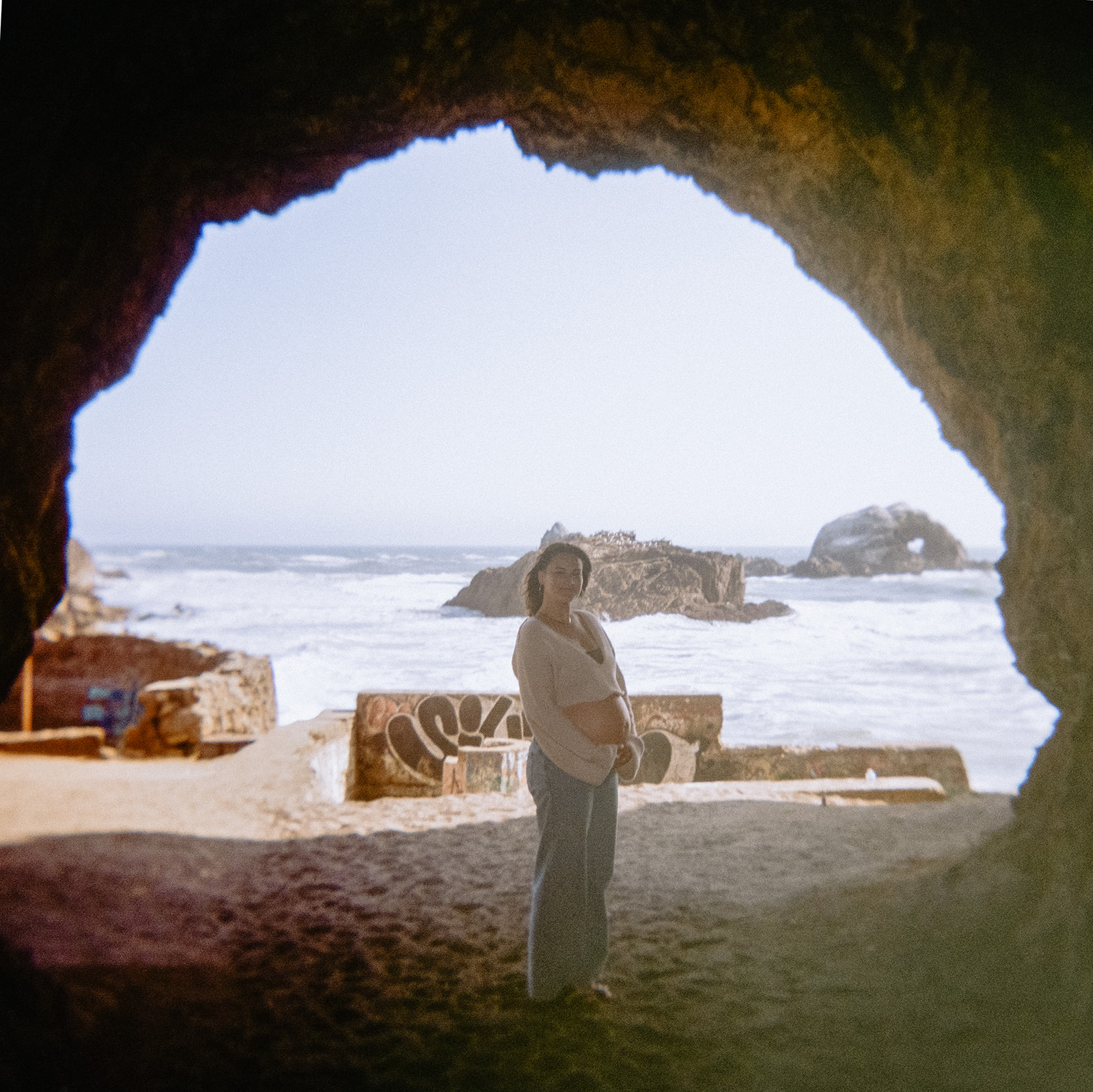 Woman posing and holding her belly at Sutro Baths for her San Francisco maternity photos.