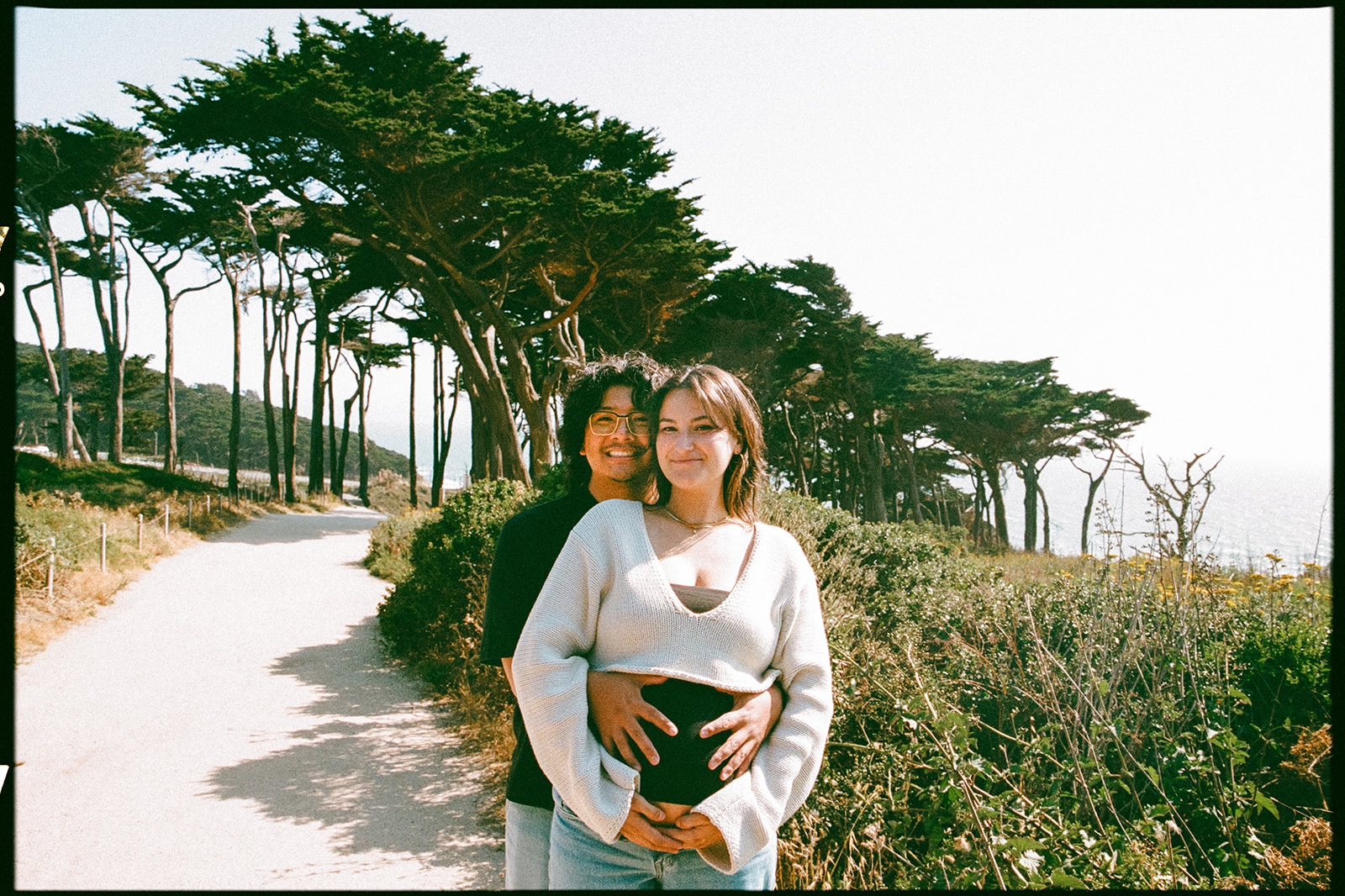Film photo of a couple smiling during their couples San Francisco maternity photos at Lands End.
