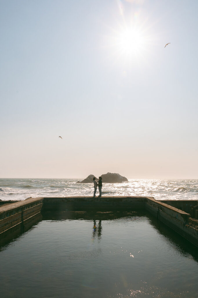 Couple posing at Sutro Baths at Lands End for San Francisco maternity photos during golden hour.