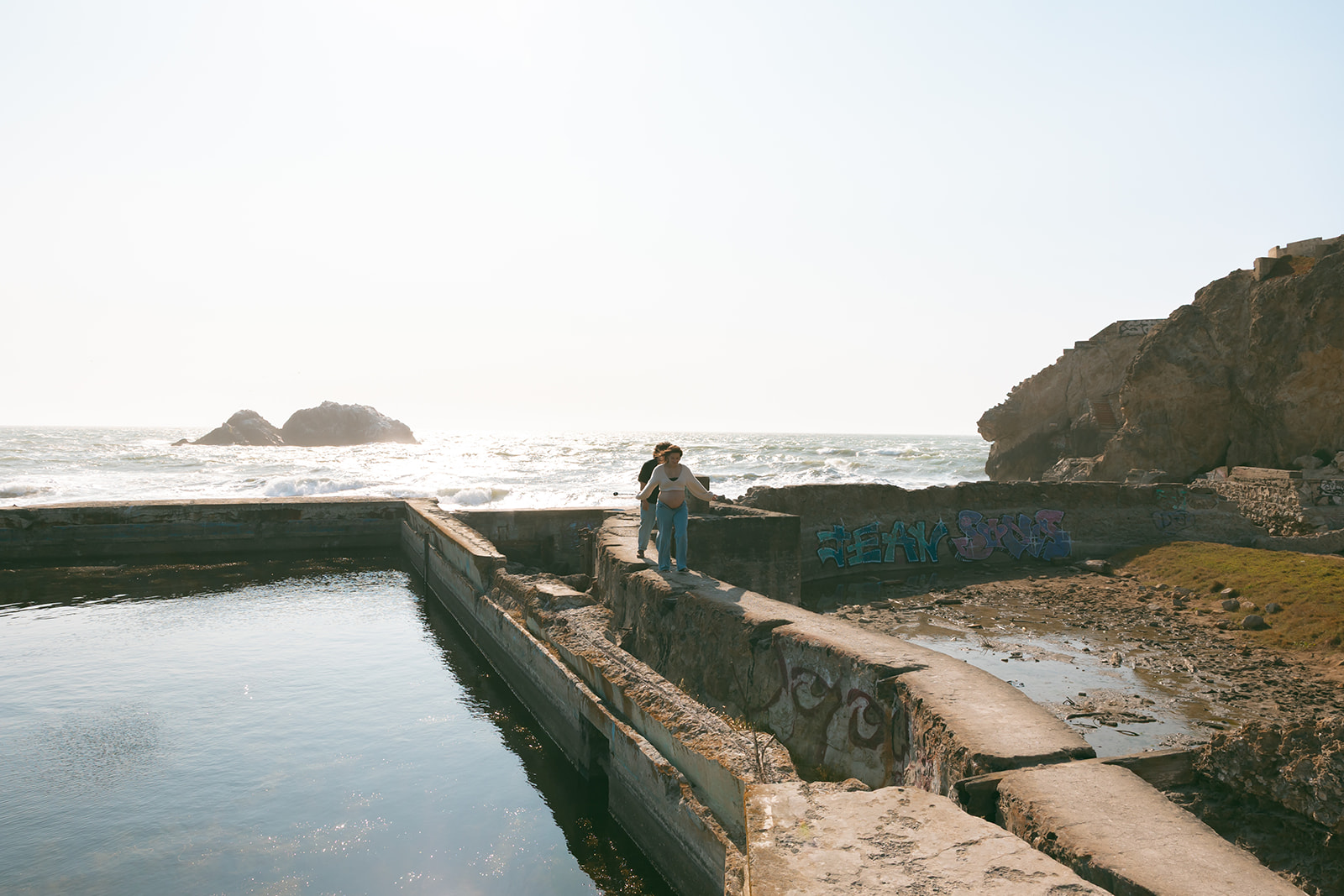 Couple walking along a wall at Sutro Baths in San Francisco.