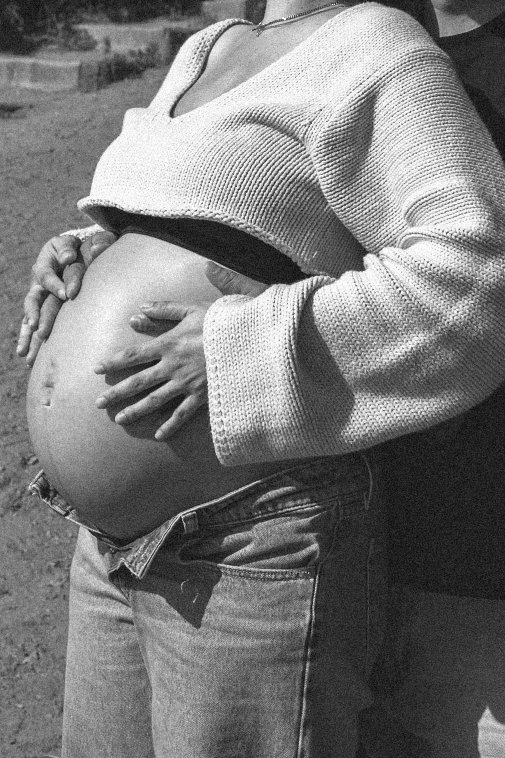 Black and white close up photo of a couple holding the woman's pregnant belly.
