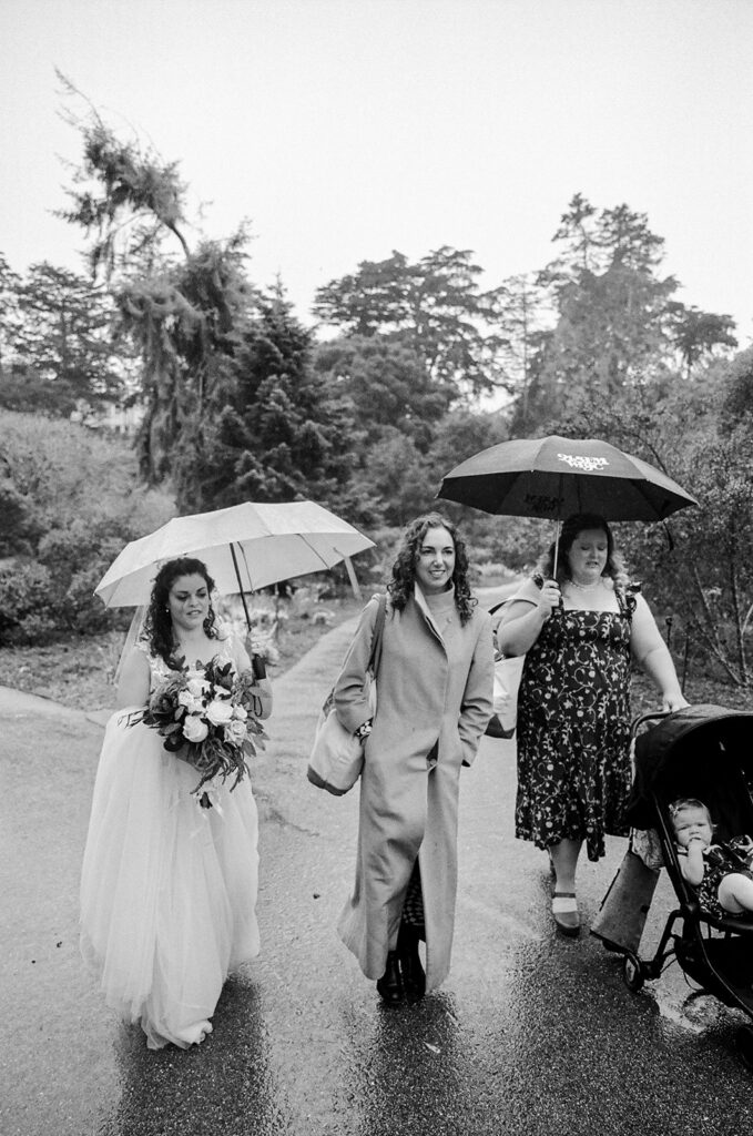 Black and white candid film photo of as bride walking with friends and family.