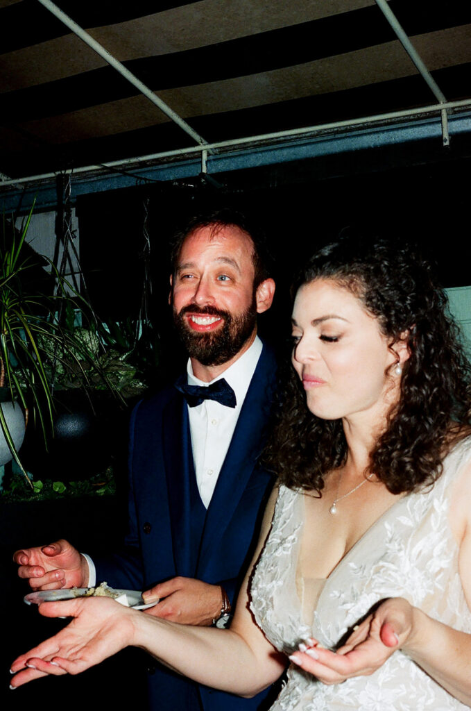 Film photo of the bride and groom cutting into their wedding cake.