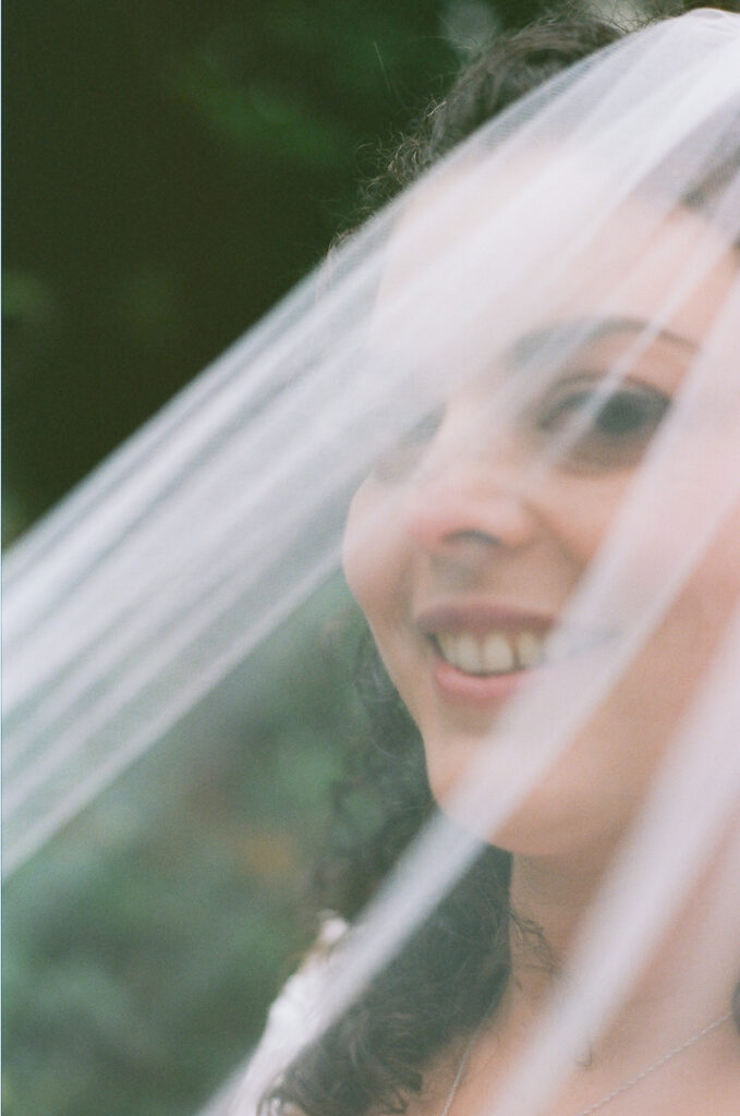 Close up photo of a bride smiling under her veil.