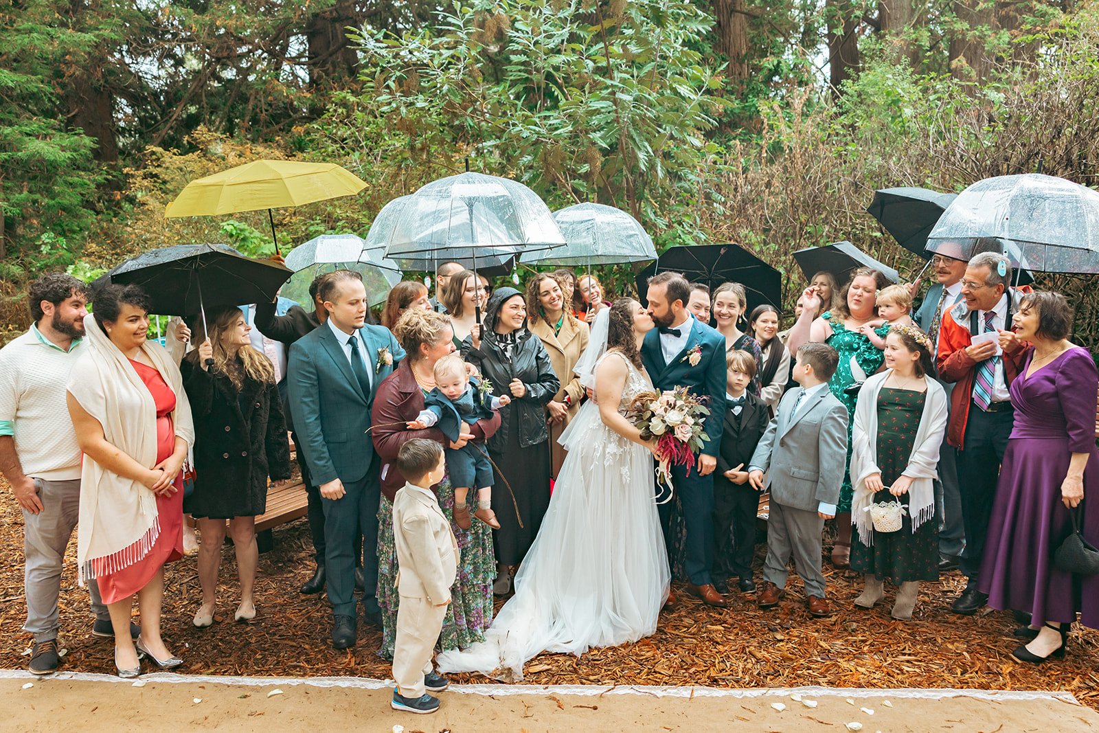 Big group shot of the bride and groom surrounded by family and friends after their San Francisco Botanical Garden wedding ceremony in Redwood Grove.