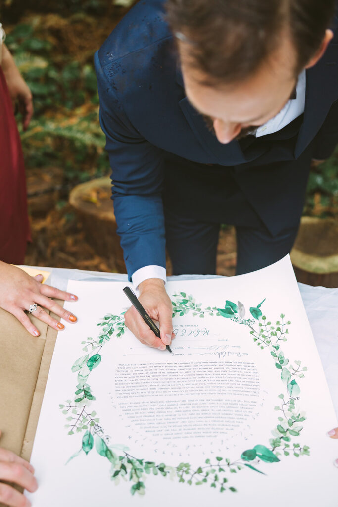 Groom signing their Ketubah. 