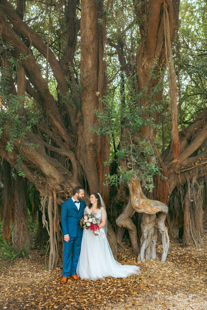 Bride and groom posing in front of trees at San Francisco Botanical Garden.