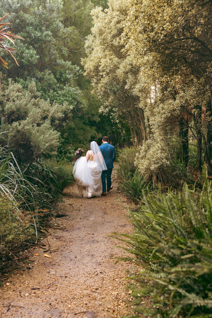 Bride and groom walking down dirt paths at San Francisco Botanical Garden.