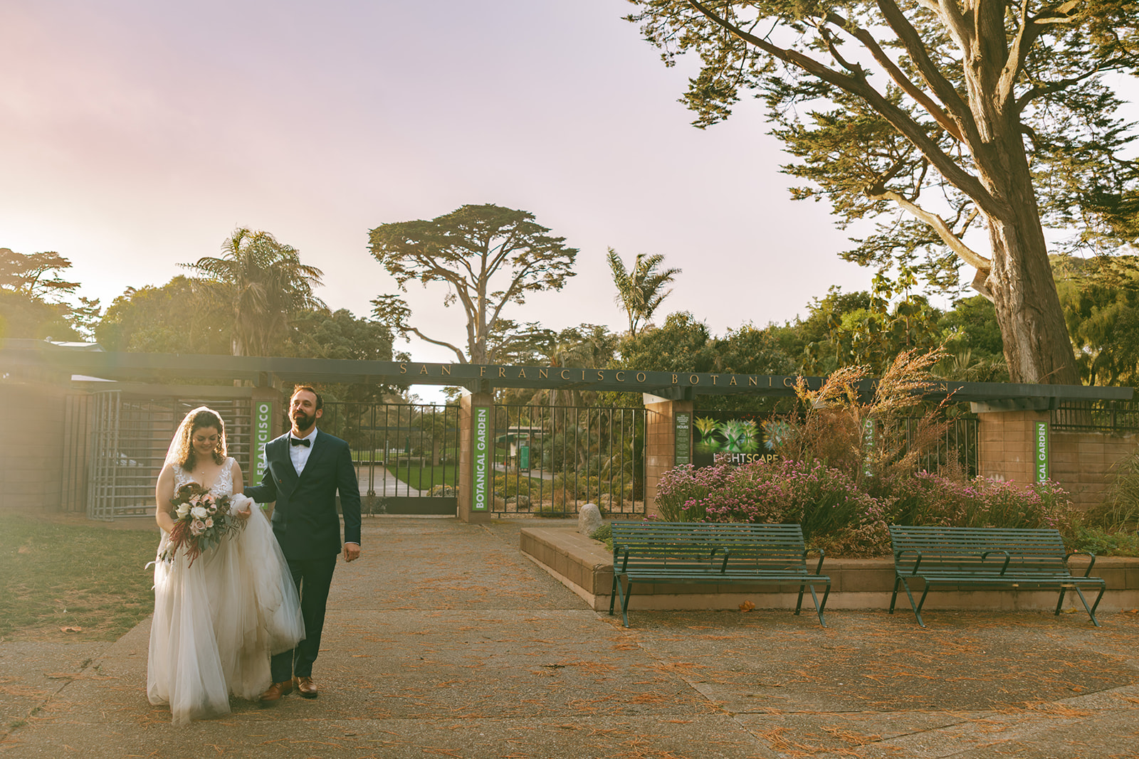 Bride and groom walking past the gate at San Francisco Botanical Garden.