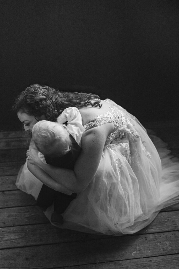 Black and white photo of the bride hugging her young son.