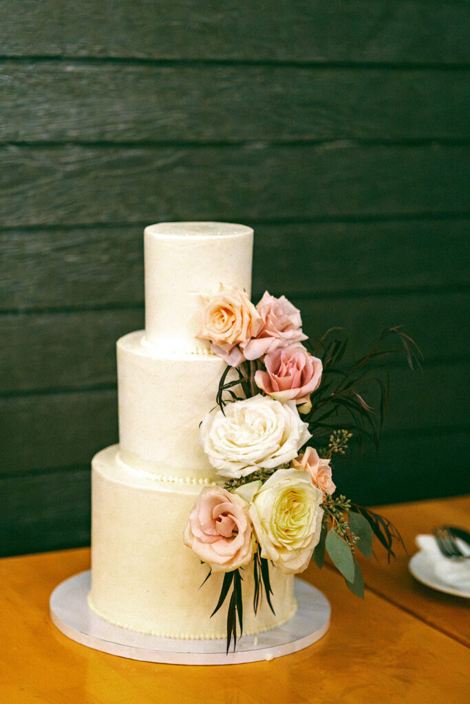 Three tiered white wedding cake with floral accents made by the bride herself.