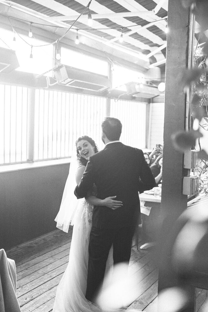 Bride smiling at the camera as she dances with the groom during their  San Francisco micro wedding reception at Fiorella.