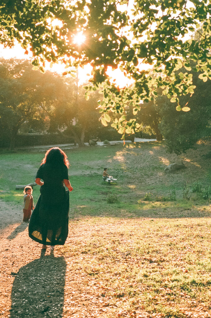 35mm film photo of a mother walking with her child through golden light at John Hinkel Park during East Bay family photos.