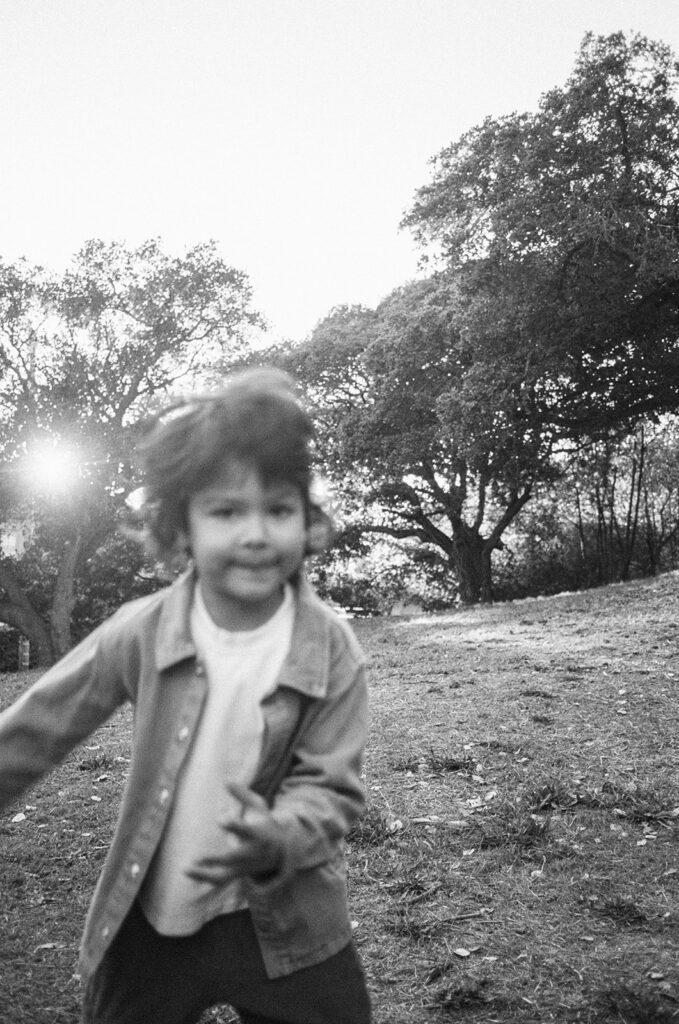 Black and white 35mm film photo of a child running through John Hinkel Park during a family session.