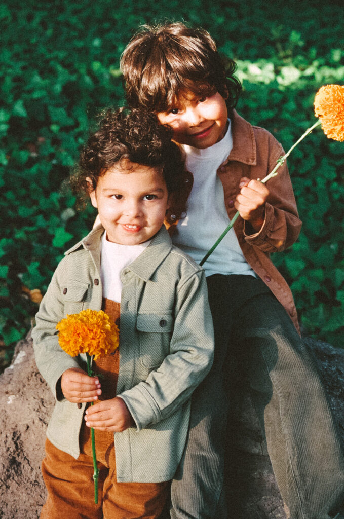 35mm film photo of two young brothers holding orange flowers during a colorful family session in the East Bay.