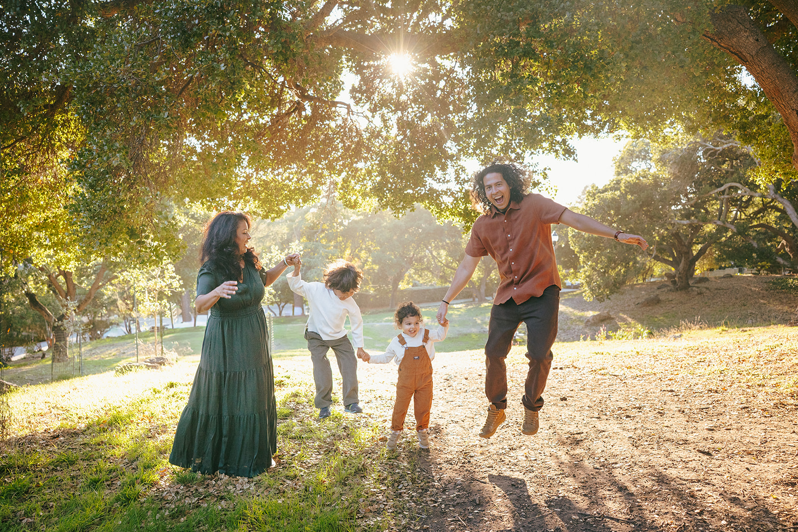 Family of four jumping in the air together during an East Bay family photo session at John Hinkel Park.