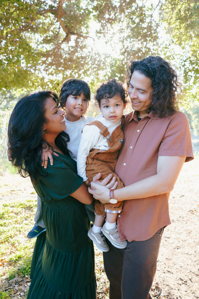 Family posing together in golden fall light during an East Bay family photo session at John Hinkel Park.