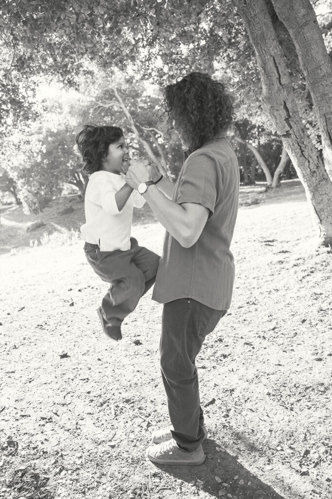 Black and white photo of a father lifting his young son up off the ground.