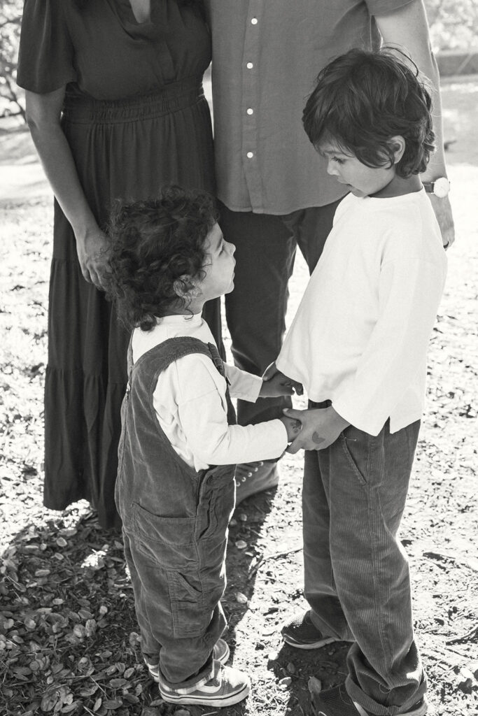 Two young brothers holding hands during candid East Bay family photos at John Hinkel Park.