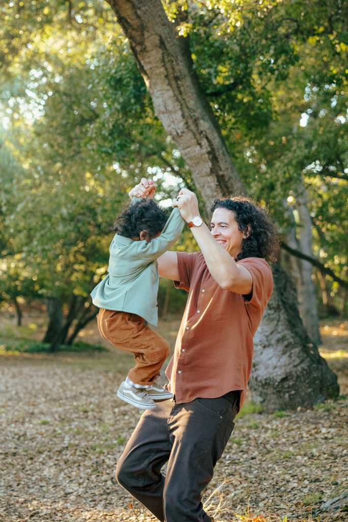 Father lifting his son in the air as they play at John Hinkel Park in the East Bay.