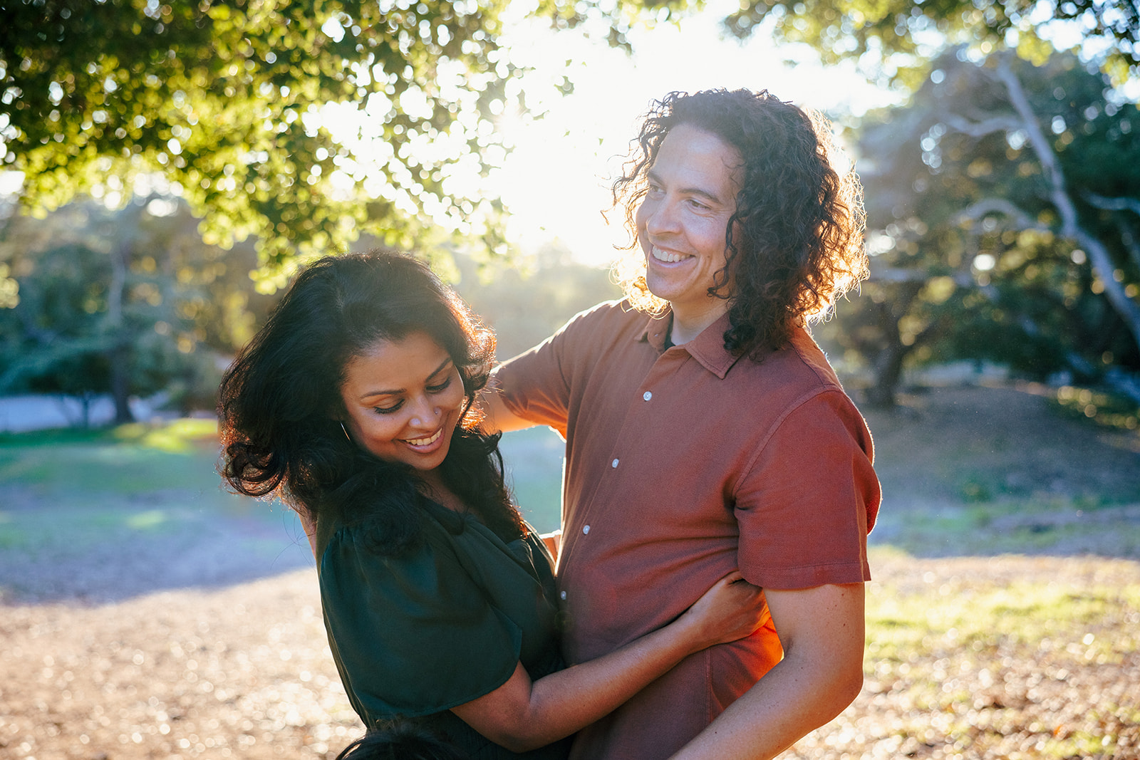 Wide shot of a couple laughing during golden hour at John Hinkel Park.