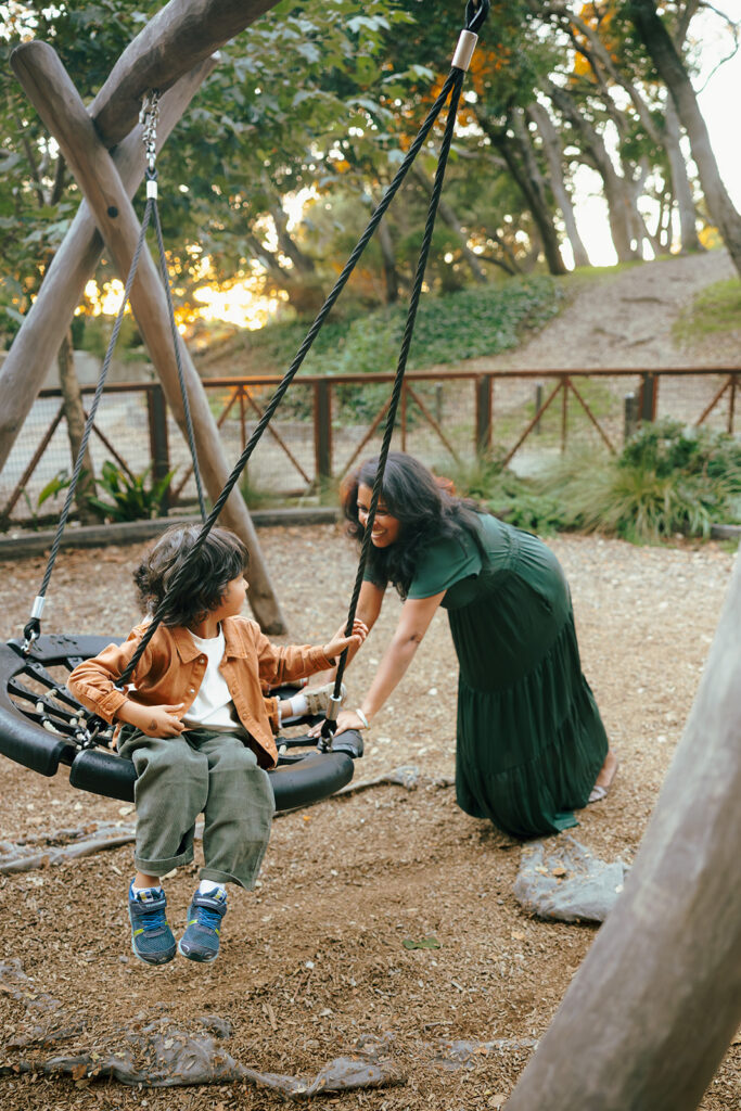 Mother smiling at her son on the swing during East Bay family photos at John Hinkel Park.