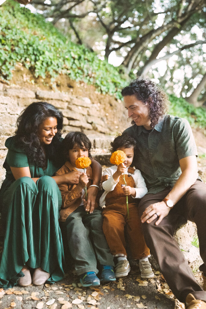 Family sitting together with orange flowers during fall East Bay family photos at John Hinkel Park.