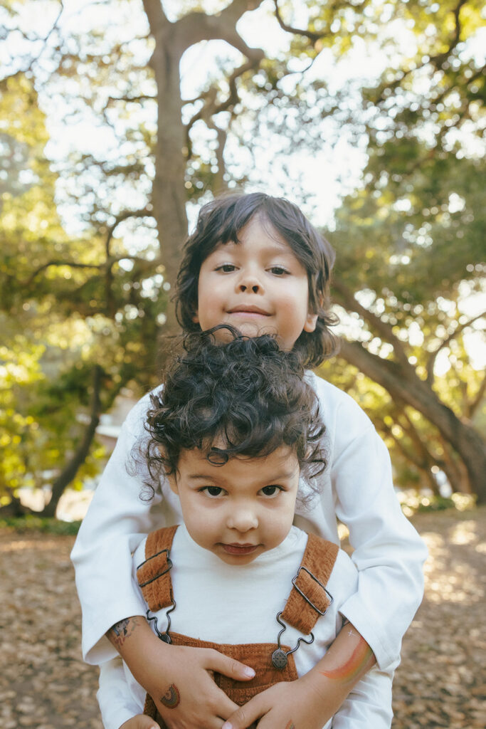 Older brother hugging his younger brother from behind during their outdoor fall family photos.